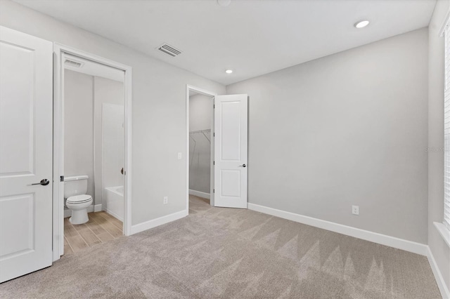 unfurnished bedroom with connected bathroom and light colored carpet