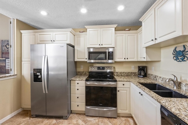 kitchen with white cabinetry, sink, light stone counters, a textured ceiling, and appliances with stainless steel finishes