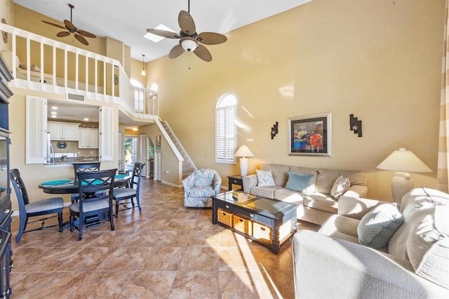 living room with ceiling fan and a towering ceiling