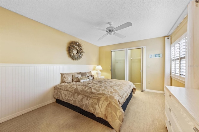 bedroom with a textured ceiling, ceiling fan, light carpet, and a closet