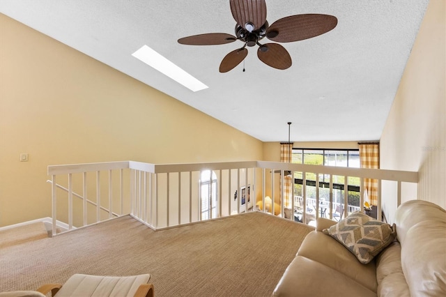 living room with a textured ceiling, ceiling fan, lofted ceiling with skylight, and carpet floors