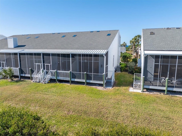 back of house with a sunroom, a lawn, and central AC