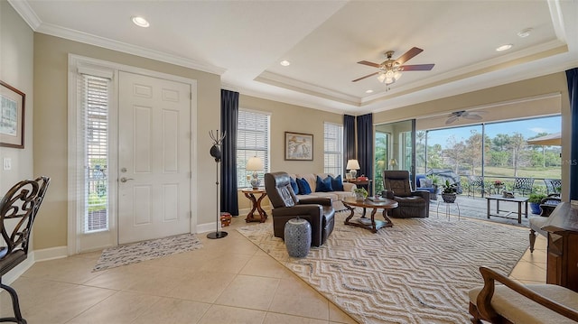 foyer with ceiling fan, a raised ceiling, light tile patterned floors, and ornamental molding