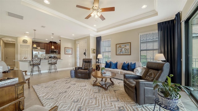 living room with ceiling fan, light tile patterned flooring, a raised ceiling, and ornamental molding