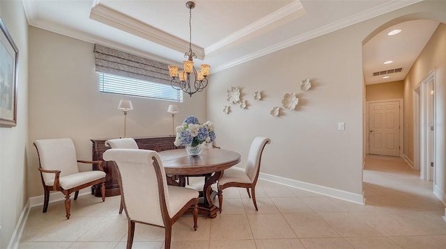 tiled dining space featuring a raised ceiling, crown molding, and a notable chandelier