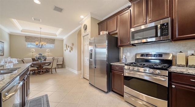 kitchen featuring stainless steel appliances, a raised ceiling, light stone counters, a notable chandelier, and light tile patterned flooring