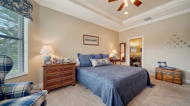 bedroom featuring ensuite bathroom, light colored carpet, a raised ceiling, ceiling fan, and crown molding