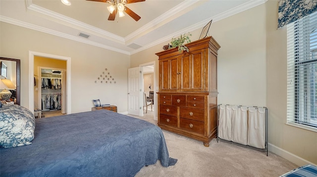 bedroom featuring ornamental molding, a tray ceiling, ceiling fan, a spacious closet, and a closet