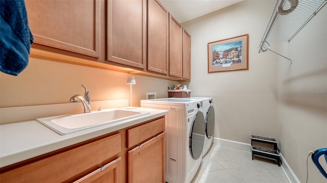 washroom with washer and clothes dryer, sink, light tile patterned floors, and cabinets