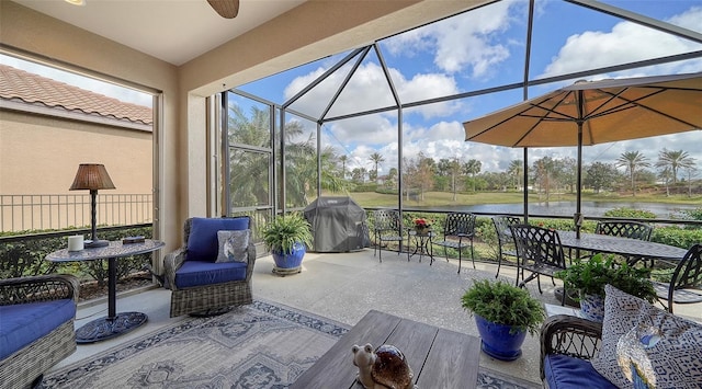 view of patio featuring glass enclosure, a grill, a water view, and ceiling fan