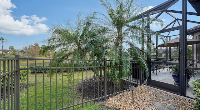 view of gate featuring a lawn and glass enclosure