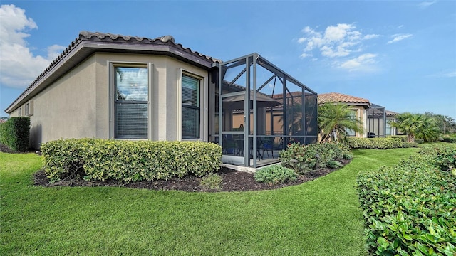 view of side of home with a lanai and a yard