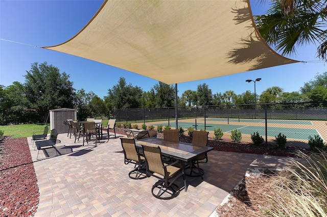 view of patio / terrace featuring tennis court and a storage unit