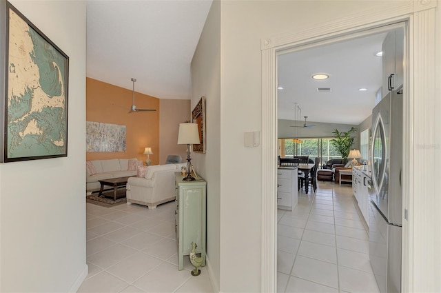 hall featuring light tile patterned floors and vaulted ceiling