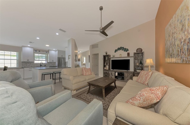 living room with ceiling fan, sink, and vaulted ceiling