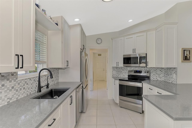 kitchen featuring sink, appliances with stainless steel finishes, light tile patterned flooring, light stone counters, and white cabinetry