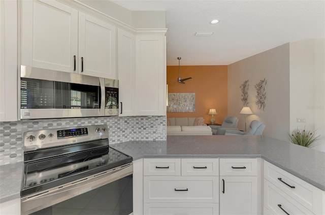 kitchen with stainless steel appliances, tile patterned floors, kitchen peninsula, decorative backsplash, and white cabinets