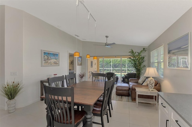 tiled dining room featuring ceiling fan, rail lighting, and vaulted ceiling