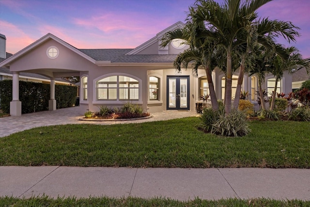 view of front of house with french doors, a carport, and a lawn