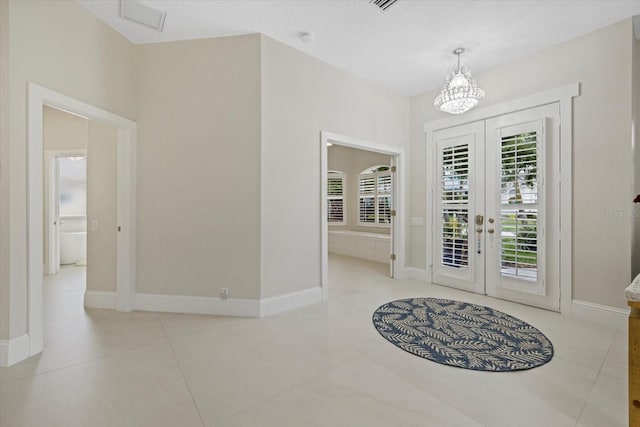 tiled entryway with a notable chandelier and french doors