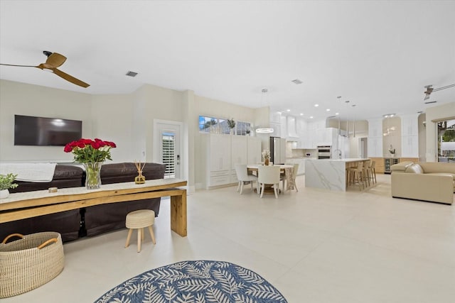 living room featuring ceiling fan, sink, and light tile patterned floors