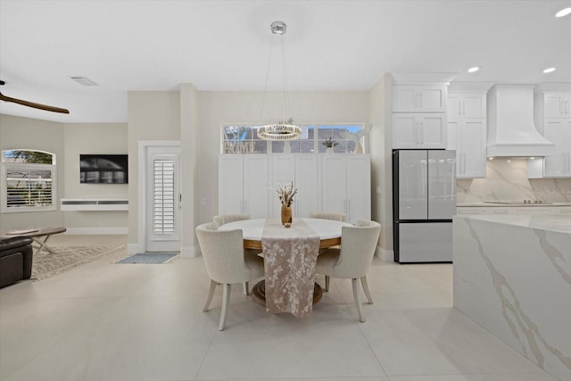 tiled dining area with ceiling fan with notable chandelier