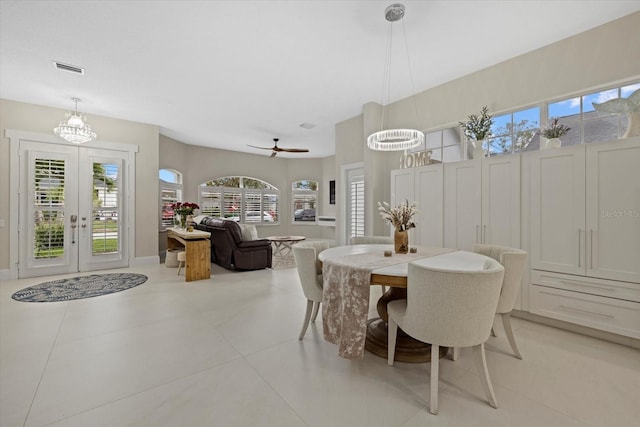 tiled dining area with french doors, a healthy amount of sunlight, and ceiling fan with notable chandelier