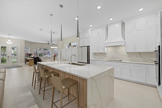 kitchen with decorative light fixtures, white cabinetry, a spacious island, and custom range hood