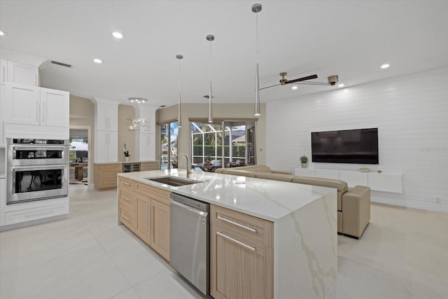 kitchen featuring light brown cabinetry, stainless steel appliances, ceiling fan, sink, and a large island