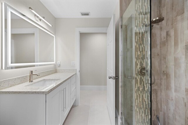 bathroom with tile patterned flooring, vanity, and walk in shower