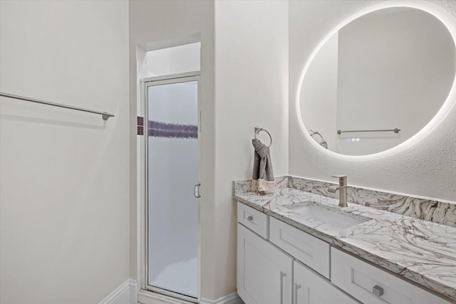 bathroom featuring a shower with door and vanity