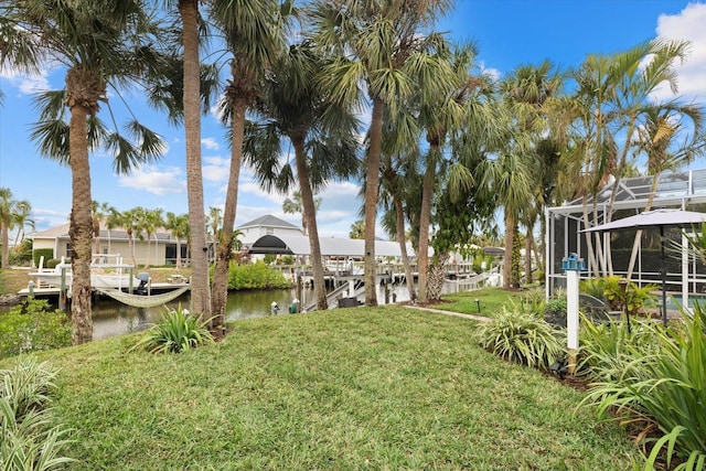 view of yard with a dock, a water view, and glass enclosure