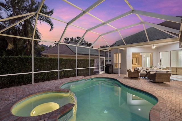 pool at dusk with a lanai, an in ground hot tub, a patio, and an outdoor hangout area