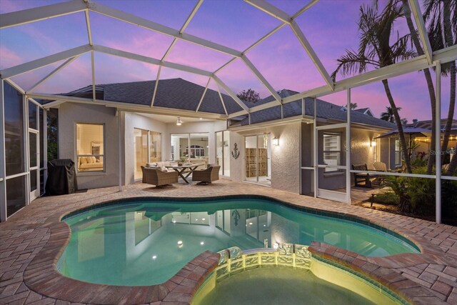 pool at dusk featuring ceiling fan, a lanai, and a patio