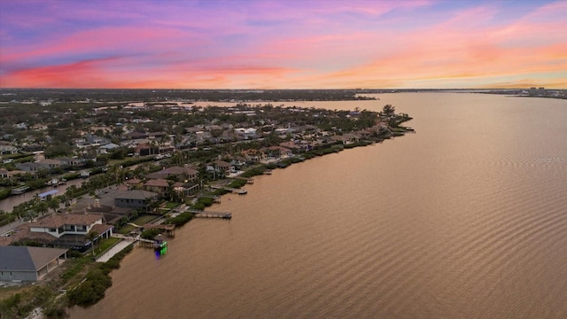 aerial view at dusk featuring a water view