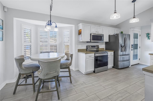 kitchen with white cabinetry, hanging light fixtures, vaulted ceiling, and appliances with stainless steel finishes