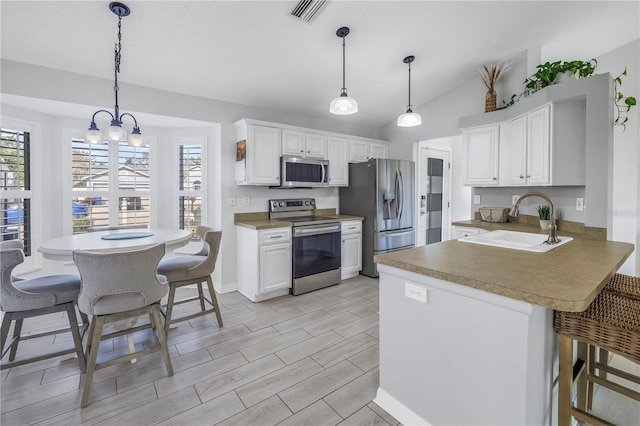 kitchen with pendant lighting, sink, white cabinetry, kitchen peninsula, and stainless steel appliances