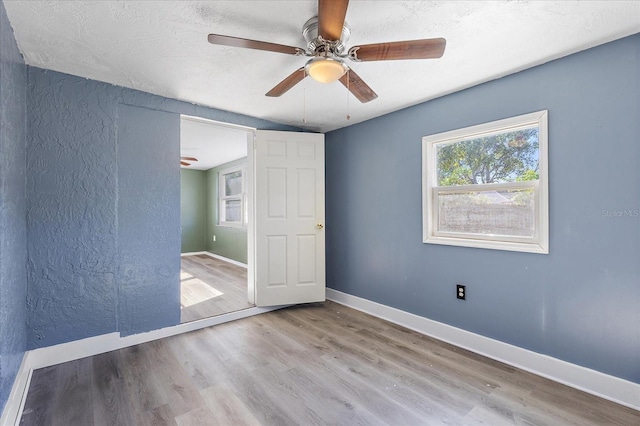 unfurnished bedroom with ceiling fan, a textured ceiling, and light wood-type flooring