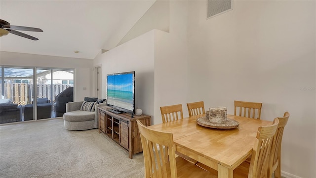 carpeted dining space with ceiling fan and high vaulted ceiling