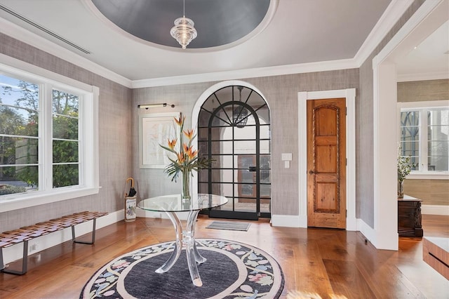 entrance foyer with a tray ceiling, wood-type flooring, and ornamental molding