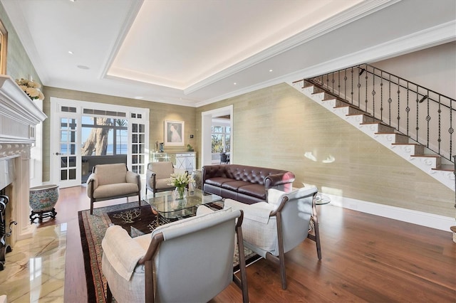 living room with a raised ceiling, a premium fireplace, wood-type flooring, and ornamental molding