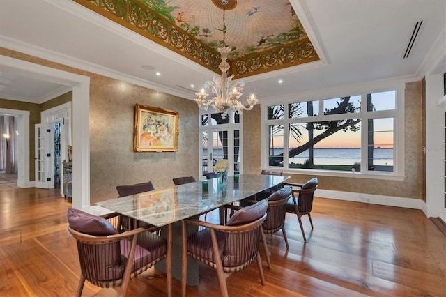 dining space featuring french doors, a tray ceiling, crown molding, a chandelier, and hardwood / wood-style floors