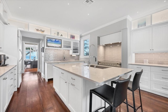 kitchen featuring a center island with sink, a breakfast bar, white cabinets, and tasteful backsplash