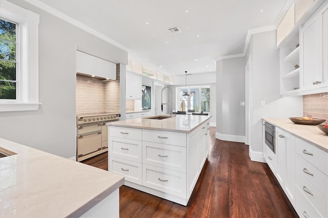 kitchen with decorative backsplash, pendant lighting, a center island with sink, white cabinets, and range with electric stovetop