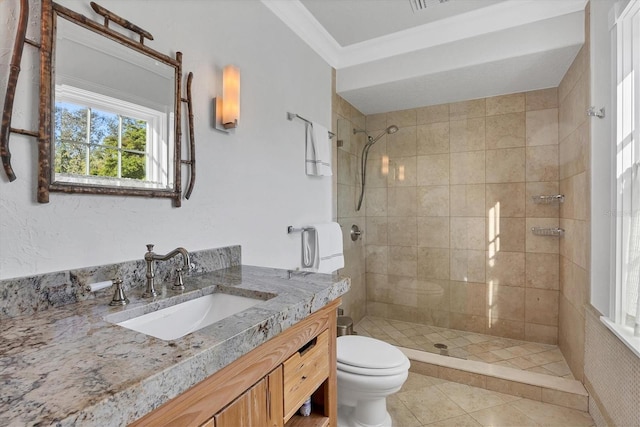 bathroom featuring vanity, crown molding, tile patterned flooring, toilet, and a tile shower