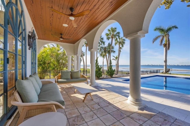 view of patio / terrace with ceiling fan, a water view, and a fenced in pool