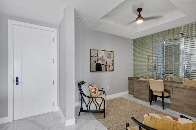 office area featuring ceiling fan, built in desk, and a tray ceiling