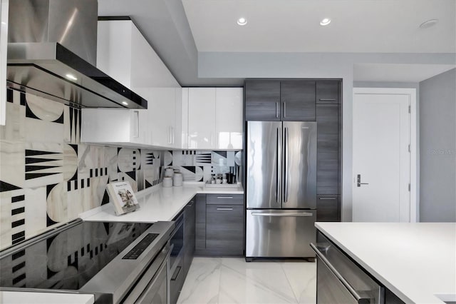 kitchen with stainless steel refrigerator, gray cabinetry, wall chimney exhaust hood, decorative backsplash, and white cabinets