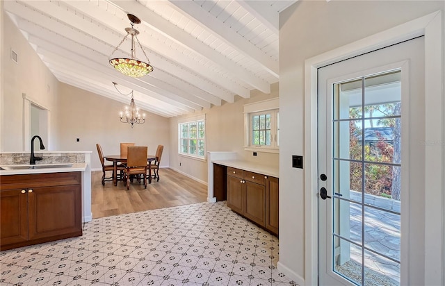 kitchen with sink, a chandelier, lofted ceiling with beams, wooden ceiling, and pendant lighting