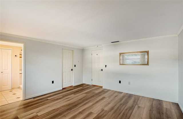 spare room featuring ornamental molding and light hardwood / wood-style floors